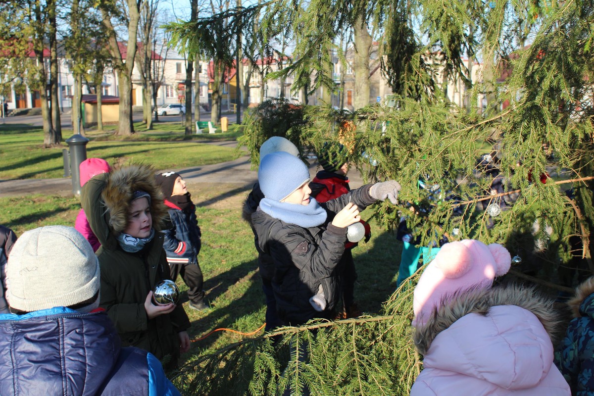 przedszkolaki ubierają choinkę w parku miejskim